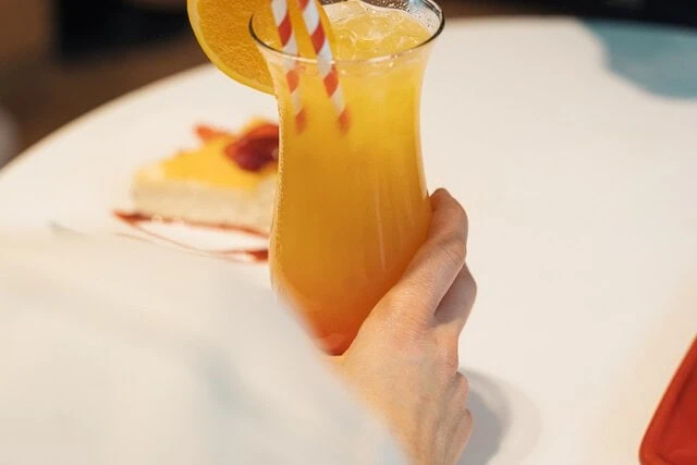 Licuado de naranja con tarta de queso al fondo